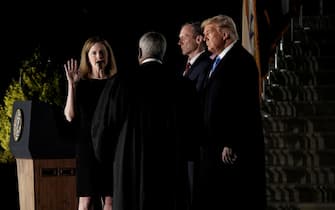 epa08776606 Associate Justice of the Supreme Court Clarence Thomas (C) administers the oath of office to Judge Amy Coney Barrett (L) to be Associate Justice of the Supreme Court on the South Lawn of the White House in Washington, DC, USA, 26 October 2020. US President Donald J. Trump (R) and her husband Jesse M. Barrett (2-R) look on.  EPA/Ken Cedeno / POOL