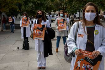 MADRID, SPAIN - OCTOBER 27: Doctors wearing protective face masks hold placards reading 'National Strike. Let's save the health service' during a protest outside the Spanish Parliament during the second wave of the coronavirus (COVID-19) pandemic on October 27, 2020 in Madrid, Spain. Doctors from across Spain are called to start a indefinite strike today, that will happen every last Tuesday of each month. Doctors are demanding better working conditions, more investment in the sector and less temporary work. (Photo by Pablo Blazquez Dominguez/Getty Images)