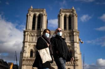 epa08775732 People wearing protective face masks walk near Notre-Dame Cathedral, in Paris, France, 26 October 2020. France is in the midst of a second wave of the COVID-19 coronavirus pandemic, recording a new high of 50,000 daily new cases - although Jean-Francois Delfraissy of France's Scientific Council estimates that bew Covid cases are rising by a rate closer to 100,000 per day. France has currently placed 45 million of its citizen across several 'departments' (counties) under a night-time curfew prohibiting leaving one's house between 9pm and 6am. French President Emmanuel Macron is convening  a defense council on 27 October to draft new measures to battle the rise in Covid-19 cases.  EPA/IAN LANGSDON