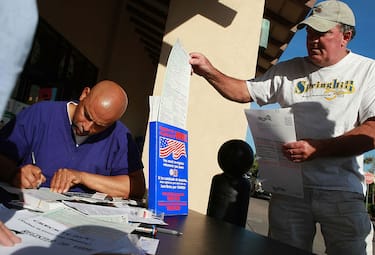 LAFAYETTE, CA - OCTOBER 20:  A man takes a voter registration card as Mario Talavera (L) registers to vote at a table sponsored by the League of Women Voters of Diablo Valley October 20, 2008 in Lafayette, California. Residents are rushing to register to vote on the final day of voter registration in California before the presidential election.  (Photo by Justin Sullivan/Getty Images)