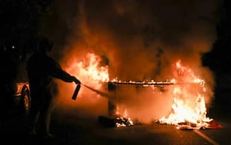 A person uses a fire extinguisher to put out a burning barricade in Philadelphia on October 27, 2020, during a protest over the police shooting of 27-year-old Black man Walter Wallace. - Hundreds of people demonstrated in Philadelphia late on October 27, with looting and violence breaking out in a second night of unrest after the latest police shooting of a Black man in the US. The fresh unrest came a day after the death of 27-year-old Walter Wallace, whose family said he suffered mental health issues. On Monday night hundreds of demonstrators took to the streets, with riot police pushing them back with shields and batons. (Photo by Gabriella AUDI / AFP) (Photo by GABRIELLA AUDI/AFP via Getty Images)