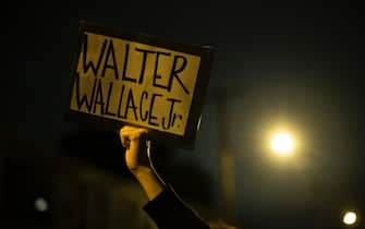 1229318612 PHILADELPHIA, PA - OCTOBER 27: A demonstrator holds a placard reading "WALTER WALLACE JR." during a protest near the location where Walter Wallace, Jr. was killed by two police officers on October 27, 2020 in Philadelphia, Pennsylvania. Protests erupted after the fatal shooting of 27-year-old Wallace Jr, who Philadelphia police officers claimed was armed with a knife. (Photo by Mark Makela/Getty Images)