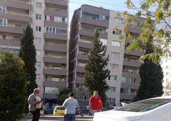 epa08785790 People stand near by a damaged building after a 7.0 magnitude earthquake in the Aegean Sea in Izmir, Turkey, 30 October 2020. According to Turkish media reports dozens of buildings were destroyed in the earthquake.  EPA/DEMIROREN NEWS AGENCY TURKEY OUT