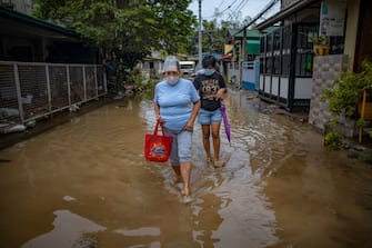 BATANGAS, PHILIPPINES - NOVEMBER 02: Residents wade through muddy floodwater caused by Typhoon Goni on November 2, 2020 in Batangas city, south of Manila, Philippines. Super Typhoon Goni, this year's most powerful storm in the world, hit the Philippines with wind gusts of up to 165 miles per hour on November 1. The typhoon left at least ten people killed. (Photo by Ezra Acayan/Getty Images)