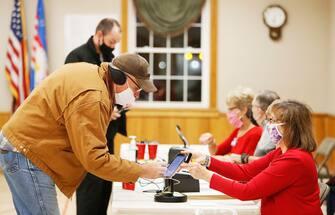 epa08795054 Gary Kuntz (L) of Edinburg, Ohio, the first voter in line at the Edinburg Town Hall polling location receives his ballot from Poll worker Debbie Stanatis (R) at a polling location at the Edinburg Town Hall in Edinburg, Ohio, USA, 03 November 2020. Americans vote on Election Day to choose between re-electing Donald J. Trump or electing Joe Biden as the 46th President of the United States to serve from 2021 through 2024.  EPA/DAVID MAXWELL