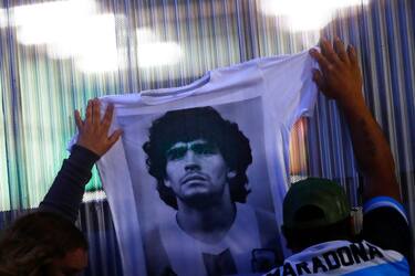 OLIVOS, ARGENTINA - NOVEMBER 03: Fans hold a jersey with the face of Diego Maradona at ClÃnica Olivos on November 03, 2020 in Olivos, Argentina. Personal doctor of Maradona, Leopoldo Luque, confirmed the former footballer will under a surgery to treat a clot in his brain. Maradona, who turned 60 on Friday 30, had spent the night of Monday hospitalized after being admitted with symptoms of depression. (Photo by Marcos Brindicci/Getty Images)