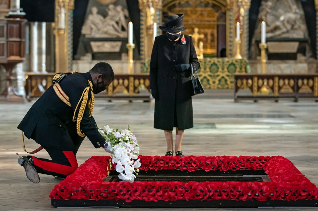 1229517325 LONDON, ENGLAND - NOVEMBER 04: The Queen's Equerry, Lieutenant Colonel Nana Kofi Twumasi-Ankrah, places a bouquet of flowers at the grave of the Unknown Warrior on behalf of Queen Elizabeth II (centre) during a ceremony in Westminster Abbey to mark the centenary of the burial of the Unknown Warrior on November 4, 2020. The grave of the Unknown Warrior is the final resting place of an unidentified British serviceman who died on the battlefields during the First World War and whose body was brought from Northern France and buried at Westminster Abbey on 11th November 1920. (Photo by Aaron Chown - WPA Pool/Getty Images)