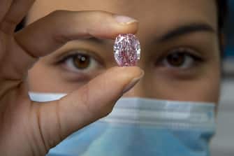epa08802994 A Sotheby's employee poses with 'The Spirit of the Rose' vivid purple-pink diamond weighing 14.83-carat, during a preview at Sotheby's in Geneva, Switzerland, 06 November 2020. The diamond will be offered for sale at an auction in Geneva on 11 November.  EPA/SALVATORE DI NOLFI