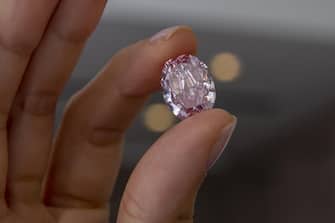 epa08802988 A Sotheby's employee poses with 'The Spirit of the Rose' vivid purple-pink diamond weighing 14.83-carat, during a preview at Sotheby's in Geneva, Switzerland, 06 November 2020. The diamond will be offered for sale at an auction in Geneva on 11 November.  EPA/SALVATORE DI NOLFI