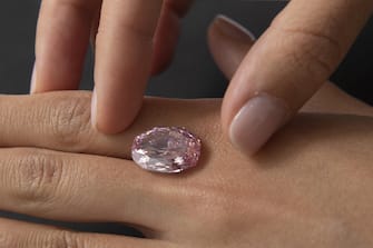epa08802990 A Sotheby's employee poses with 'The Spirit of the Rose' vivid purple-pink diamond weighing 14.83-carat, during a preview at Sotheby's in Geneva, Switzerland, 06 November 2020. The diamond will be offered for sale at an auction in Geneva on 11 November.  EPA/SALVATORE DI NOLFI