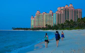 NASSAU, THE BAHAMAS - JUNE 15: Women are walking barefoot on the beach of Paradise Island to the buildings of Atlantis Hotel while sunset on June 15, 2012 in Nassau, The Bahamas. (Photo by EyesWideOpen/Getty Images)
