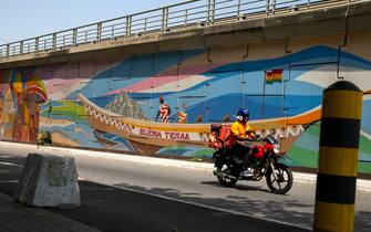 epa08741482 A motorcyclist rides past a mural on the walls of Ako Adjei interchange in Accra, Ghana, 13 October 2020. Giant murals by the creative Art Council of Ghana and the association of Visual Artists have been painted by over 30 painters on the walls of Ako Adjei, Tetteh Quarshi and Kanda interchanges in Accra. The works incorporate elements of traditional Ga Adangbe culture and portray the culture and traditions of the people of Ghana. Equally depicted are spiritual practices, reverence for the ocean and the universe, philosophical thoughts, cleansing rituals, symbols of communication, theatrical aesthetics and visual representations of mythical imaginations.  EPA/CHRISTIAN THOMPSON