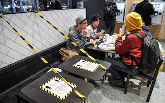 Guests enjoy their meal at a fast food restaurant next to taped off tables in central Stockholm on November 12, 2020, amid the ongoing novel coronavirus (Covid-19) pandemic. - The Swedish government has proposed a stop for the sale of alcohol after 10 pm from November 20 until the end of February, to curb the spread of the virus. Faced with the worsening of the Covid-19 epidemic in the country, the Swedish government on November 11 urged the population to follow health rules, although they are not coercive. (Photo by Fredrik SANDBERG / TT News Agency / AFP) / Sweden OUT (Photo by FREDRIK SANDBERG/TT News Agency/AFP via Getty Images)