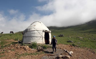 epa04305817 A Kyrgyz boy walks in front of a typical yurta tent in a nomad camp located some 230 kilometers south of Bishkek, about 3,000 meters above sea level in a high steppe plateau of the Suusamyr Valley, Kyrgyzstan, 08 July 2014. The valley in Kyrgyzstan is famous for its 'Kumis', a fermented dairy product is traditionally made from mares' milk. Kumis is still part of the traditional daily nutrition of the nomad peoples. It is said to even help to cure tuberculosis and anemia and was a popular treatment in specialized Kumis sanatoriums in Russia in the 19th century.  EPA/IGOR KOVALENKO