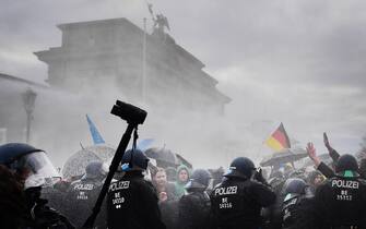 epa08827212 Riot police tries to break up a demonstration against German coronavirus restrictions in front of the Brandenburg Gate in Berlin, Germany, 18 November 2020. While German interior minister prohibited demonstrations around the Reichstag building during the parliamentary Bundestag session people gathered to protest against government-imposed semi-lockdown measures aimed at curbing the spread of the coronavirus pandemic. Since 02 November, all restaurants, bars, cultural venues, fitness studious, cinemas and sports halls are forced to close for four weeks as a lockdown measure to rein in skyrocketing coronavirus infection rates.  EPA/FILIP SINGER
