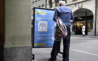 Un signore legge un cartello con le misure anti-covid in Svizzera