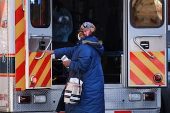 NEW YORK, NY - APRIL 11: A relative stands near to a patient being taken away in an ambulance on April 11, 2020 in the Brooklyn borough of New York City. According to John Hopkins University, the global death toll from COVID-19 has now reached 100,000 worldwide with many experts believing that the number is actually higher.   Spencer Platt/Getty Images/AFP
== FOR NEWSPAPERS, INTERNET, TELCOS & TELEVISION USE ONLY ==