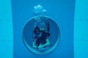 1229726868 A diver is seen in the deepest pool in the world with 45.5-metre (150-foot) located in Mszczonow about 50 km from Warsaw, November 21, 2020. - The complex, named Deepspot, even includes a small wreck for scuba and free divers to explore. It has 8,000 cubic metres of water -- more than 20 times the amount in an ordinary 25-metre pool. (Photo by Wojtek RADWANSKI / AFP) (Photo by WOJTEK RADWANSKI/AFP via Getty Images)