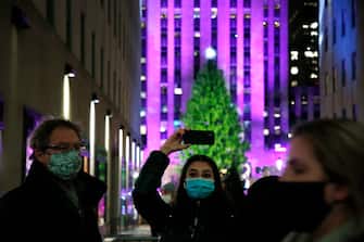 NEW YORK, NEW YORK - DECEMBER 02: People take photos of the Christmas tree during the 87th Annual Rockefeller Center Christmas Tree Lighting Ceremony at Rockefeller Center on December 02, 2020 in New York City. (Photo by John Lamparski/Getty Images)