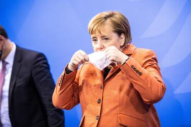 epaselect epa08881126 German Chancellor Angela Merkel puts her face mask on during a press conference after a video conference with German State Premiers about increased anti-coronavirus measures to be implemented on upcoming 16 December, in Berlin, Germany, 13 December 2020. EPA/RAINER KEUENHOF / POOL