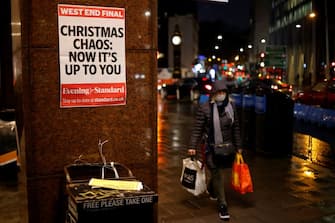 A shopper wears a facemask as she walks past an Evening Standard newspaper stand at Victoria Station in central London on December 16, 2020, as new guidance on Christmas during the novel coronavirus COVID-19 pandemic was announced by the government. - Prime Minister Boris Johnson resisted calls to tighten coronavirus restrictions over Christmas, as London faced stricter measures and concern mounted about case numbers. (Photo by Tolga Akmen / AFP) (Photo by TOLGA AKMEN/AFP via Getty Images)