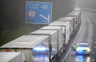 epa08897803 A police car patrols lorries headed to the Port of Dover which are stacked along the M20 motorway in Kent, Britain, 21 December 2020. France has closed its border with the UK for 48 hours over concerns about the new coronavirus variant. Freight lorries cannot cross by sea or through the Eurotunnel and the Port of Dover has closed to outbound traffic.  EPA/NEIL HALL