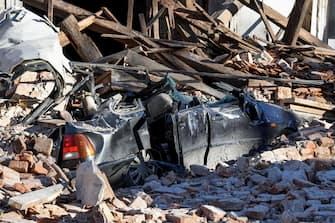 This photograph taken on December 29, 2020, shows the wreckage of a car and damaged buildings in Petrinja, some 50kms from Zagreb, after the town was hit by an earthquake of the magnitude of 6,4. - The tremor, one of the strongest to rock Croatia in recent years, collapsed rooftops in Petrinja, home to some 20,000 people, and left the streets strewn with bricks and other debris. Rescue workers and the army were deployed to search for trapped residents, as a girl was reported dead. (Photo by DENIS LOVROVIC / AFP)