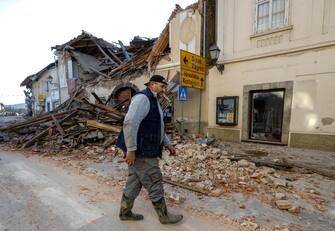 epa08909588 A man stands on a street next to destroyed houses in an earthquake in Petrinja, Croatia, 29 December 2020. A 6.4 magnitude earthquake struck around 3km west south west of the town with reports of many injuries and at least one death.  EPA/ANTONIO BAT