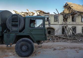 epa08909545 Croatian military truck pass in front of the buildings damaged in an earthquake, in Petrinja, Croatia, 29 December 2020. A 6.4 magnitude earthquake struck around 3km west south west of the town with reports of many injuries and at least one death.  EPA/ANTONIO BAT