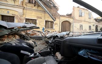 A picture shows a car damaged by the rubbles of a collapsed building in Petrinja, some 50kms from Zagreb, after the town was hit by an earthquake of the magnitude of 6,4 on December 29, 2020. - The tremor, one of the strongest to rock Croatia in recent years, collapsed rooftops in Petrinja, home to some 20,000 people, and left the streets strewn with bricks and other debris. Rescue workers and the army were deployed to search for trapped residents, as a girl was reported dead. (Photo by DENIS LOVROVIC / AFP)
