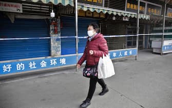 epa08143670 A woman wears a mask while walking past the closed Huanan Seafood Wholesale Market, which has been linked to cases of a new strain of Coronavirus identified as the cause of the pneumonia outbreak in Wuhan, Hubei province, China, 20 January 2020. China reported on 20 January an additional death and surge of 139 new confirmed cases of the mysterious SARS-like virus linked to the Wuhan pneumonia outbreak, bringing the total number of cases to 198 with three deaths so far.  EPA/STR CHINA OUT