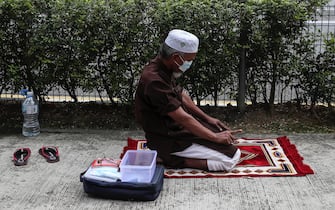 epa08932451 A Muslim man prays on a roadside in Kuala Lumpur, Malaysia, 12 January 2021. According to media reports on 12 January, the King of Malaysia declared a state of emergency in the country in an attempt to halt the spread of the coronavirus disease (COVID-19) pandemic. The state of emergency will last until 01 August, but can be lifted earlier if infection rates decrease.  EPA/FAZRY ISMAIL