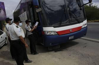 RIO HONDO, GUATEMALA - JANUARY 18: Police officers check a bus at a registration booth on January 18, 2021 in Rio Hondo, Zacapa, Guatemala. The caravan departed from Honduras to walk across Guatemala and Mexico to eventually reach the United States. After clashing with the police yesterday migrants are being held to carry out immigration and heath controls. Central Americans expect to receive asylum and most Hondurans decided to migrate after being hit by recent hurricanes.  (Photo by Josue Decavele/Getty Images)