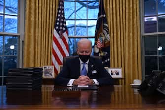 TOPSHOT - US President Joe Biden sits in the Oval Office at the White House in Washington, DC, after being sworn in at the US Capitol on January 20, 2021. - US President Joe Biden signed a raft of executive orders to launch his administration, including a decision to rejoin the Paris climate accord. The orders were aimed at reversing decisions by his predecessor, reversing the process of leaving the World Health Organization, ending the ban on entries from mostly Muslim-majority countries, bolstering environmental protections and strengthening the fight against Covid-19. (Photo by Jim WATSON / AFP)