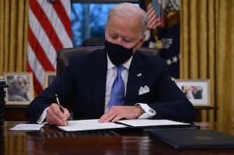 US President Joe Biden sits in the Oval Office as he signs a series of orders at the White House in Washington, DC, after being sworn in at the US Capitol on January 20, 2021. - US President Joe Biden signed a raft of executive orders to launch his administration, including a decision to rejoin the Paris climate accord. The orders were aimed at reversing decisions by his predecessor, reversing the process of leaving the World Health Organization, ending the ban on entries from mostly Muslim-majority countries, bolstering environmental protections and strengthening the fight against Covid-19. (Photo by Jim WATSON / AFP) (Photo by JIM WATSON/AFP via Getty Images)