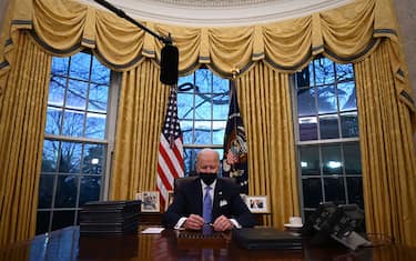 TOPSHOT - US President Joe Biden holds a pen as he prepares to sign a series of orders in the Oval Office of the White House in Washington, DC, after being sworn in at the US Capitol on January 20, 2021. - US President Joe Biden signed a raft of executive orders to launch his administration, including a decision to rejoin the Paris climate accord. The orders were aimed at reversing decisions by his predecessor, reversing the process of leaving the World Health Organization, ending the ban on entries from mostly Muslim-majority countries, bolstering environmental protections and strengthening the fight against Covid-19. (Photo by Jim WATSON / AFP) (Photo by JIM WATSON/AFP via Getty Images)