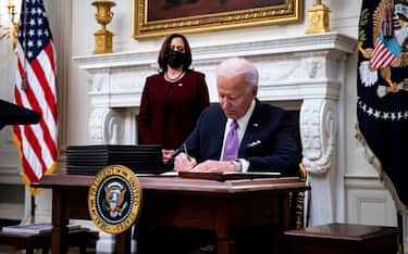 epa08956525 US President Joe Biden signs an executive order after speaking during an event on his administration's Covid-19 response with U.S. Vice President Kamala Harris, left, in the State Dining Room of the White House in Washington, DC, USA, on 21 January 2021. Biden in his first full day in office plans to issue a sweeping set of executive orders to tackle the raging Covid-19 pandemic to rapidly reverse or refashion many of his predecessor's most heavily criticized policies.  EPA/Al Drago / POOL
