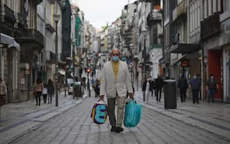 Un uomo con la mascherina passeggia per le vie di una città in Portogallo