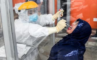 epaselect epa08963596 A healthcare worker in a hazmat suit collects specimen samples through plexiglas during a COVID-19 swab test in Medan, North Sumatra, Indonesia, 25 January 2021. Indonesia has recorded nearly one million coronavirus disease (COVID-19) cases since the beginning of the pandemic.  EPA/DEDI SINUHAJI