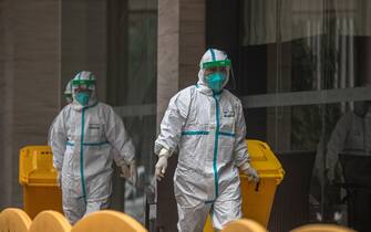 epa08970207 Workers in protective gear walk next to Jade Boutique hotel where members of World Health Organization (WHO) team have the mandatory 14-day quarantine, in Wuhan, China, 28 January 2021. The international expert team from the World Health Organization (WHO) is scheduled to conclude their 14-day quarantine on 28 January in Wuhan and will begin to investigate the origin of COVID-19.  EPA/ROMAN PILIPEY