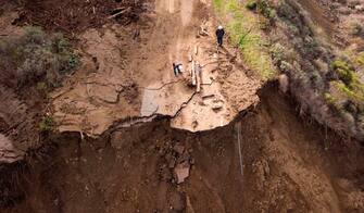 Workers assess the scene where a section of Highway 1 collapsed into the Pacific Ocean near Big Sur, California on January 31, 2021. - Heavy rains caused debris flows of trees, boulders and mud that washed out a 150-foot section of the road. (Photo by JOSH EDELSON / AFP) (Photo by JOSH EDELSON/AFP via Getty Images)