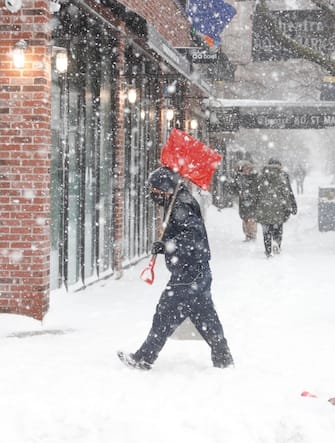 epa08980178 A man walks with a shovel through the snow along the St. Mark's area, during a snowstorm in New York, New York, USA, 01 February 2021. According to reports, the moving storm brought about 15 cm (6 inches) of snow already and is expect to bring up to 50 cm (about 20 inches) of snow by Tuesday 02 February. The storm is causing hazardous travel conditions, flight cancellations.  EPA/JASON SZENES