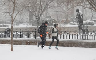 epa08980137 Two people are seen jogging through the snow past the Mohandas Gandhi Statue (R) along Union Square in New York, USA, 01 February 2021.   According to reports, the moving storm brought about 15 cm (6 inches) of snow already and is expect to bring up to 50 cm (about 20 inches) of snow by Tuesday 02 February. The storm is causing hazardous travel conditions, flight cancellations.  EPA/JASON SZENES