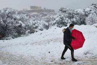 epa09015820 A man makes his way on Filoppapos hill, across Acropolis during heavy snowfall, in Athens, Greece, 16 February 2021. As the cold front Medea sweeping over Greece was in full progress and heading south, very low temperatures were recorded in the northern parts of the country.  EPA/ORESTIS PANAGIOTOU