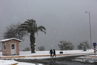 epa09016285 Two women walk during heavy snowfall in the coastal suburb of Lagonissi, near Athens, Greece, 16 February 2021. As the cold front 'Medea' is sweeping over Greece in full progress and heading south, very low temperatures were recorded in the northern parts of the country.  EPA/YANNIS KOLESIDIS