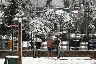 epa09015964 A winter swimmer takes a shower in the showers of Alimos beach as the heavy snowfall continues in the southern suburbs of Athens, Greece, 16 February 2021. The severe bad weather continues with intense phenomena and heavy snowfall that have closed many roads and have created intense problems in transportation.  EPA/ALEXANDER BELTES