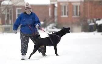 Feb 15, 2021; Cincinnati, OH, USA; Molly Wellbrock walks her dog, Stormy, through the snow storm in West Price Hill on Monday, Feb. 15, 2021. The National Weather Service issued a winter storm warning starting Monday and going through 1 p.m. Tuesday. Heavy is snow expected, with total snow accumulations of 8-12 inches in Cincinnati, according to the National Weather Service.  Mandatory Credit: Albert Cesare-USA TODAY NETWORK/Sipa USA
