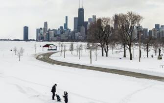 epa09017072 An aerial photo made with a drone shows people in the snow by Lake Michigan after an overnight snowfall left more than 18 inches (45.72cm) on the ground and roadways in Chicago, Illinois, USA, 16 February 2021. Much of the US has been in the grip of winter storms that have sent temperatures plummeting, closed major airports, and caused power outages to millions of people.  EPA/TANNEN MAURY