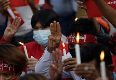 epa09012306 Demonstrators holding candles raise three-fingers salute signs during a prayer for a protestor girl, named Mya Thwe Thwe Khaing who was shot by policeman in Naypyitaw causing the brain dead, in front of Yangon city in Yangon, Myanmar, 14 February 2021.  EPA/LYNN BO BO