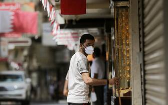 epa08310120 A man wearing a protective face mask stands in front of his gold jewellery shop in a street of Manama, Bahrain, 20 March 2020. According to media sources, Bahrain on 19 March 2020 reported some 269 cases that tested positive to the COVID-19 coronavirus disease. All types of education facilities, gyms, cinemas, and restaurants were closed amid the coronavirus COVID-19 pandemic.  EPA/AHMED ALFARADAN